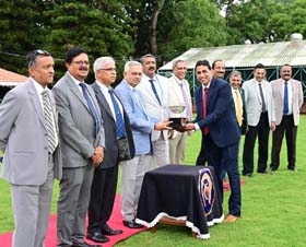 Chairman of Mysore Race Club G Venkatesh presenting the S V Subramaniam Memorial Trophy to trainer Vinesh V Naik after his ward Pure For Sure won this event at Mysore on Wednesday.